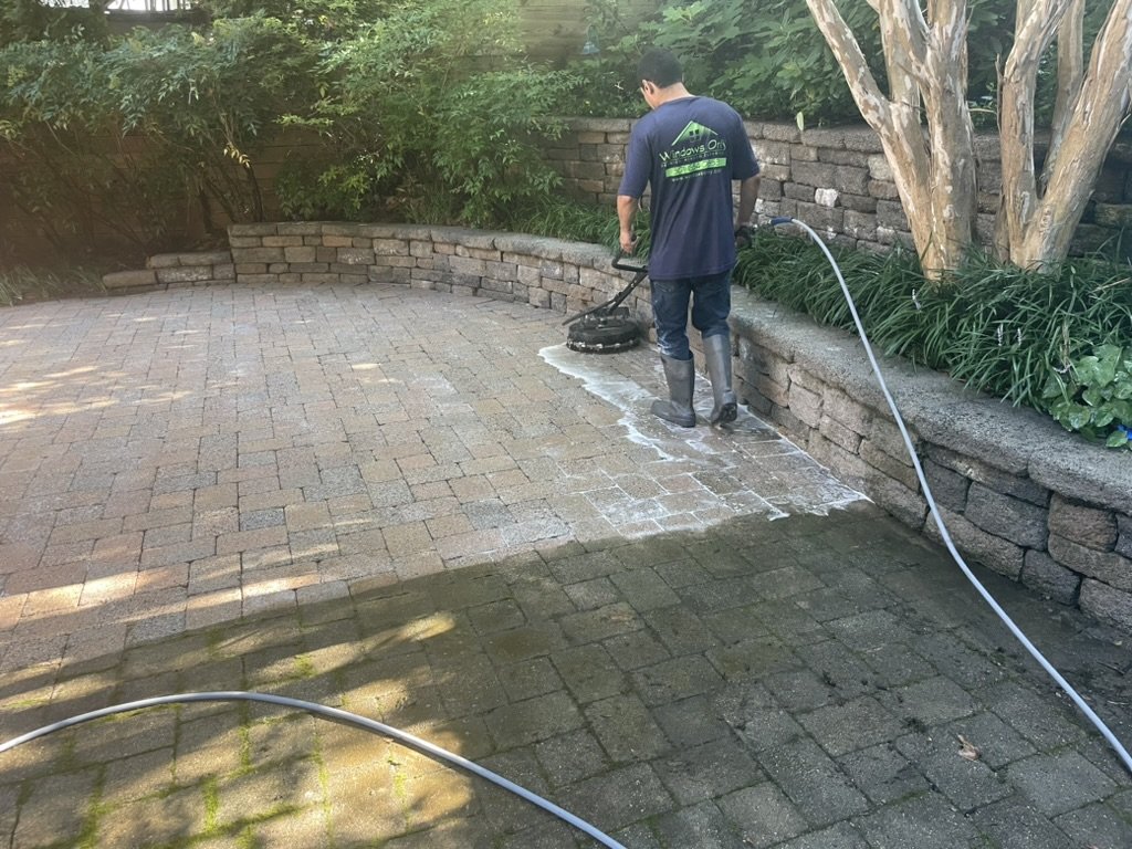 Windows Only crew pressure washing a paver patio, clean and dirty sections side by side