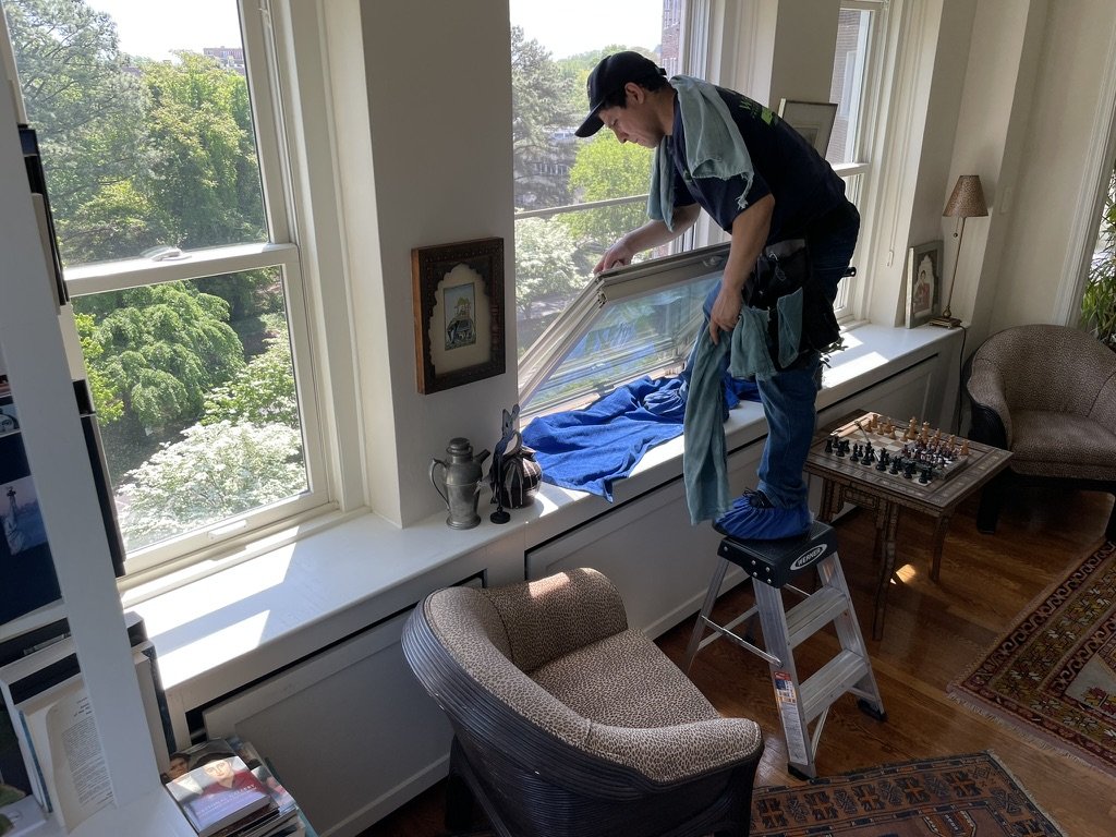 Windows Only crew cleaning windows inside an apartment, wearing shoe covers